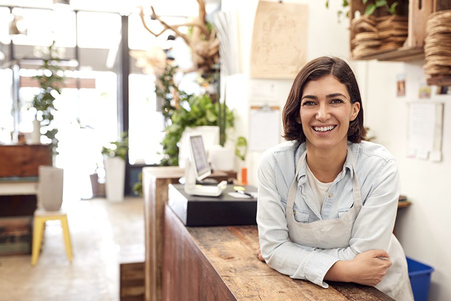 Business Insurance - Portrait Of Smiling Female Associate Standing Behind Sales Desk Of Florist Store