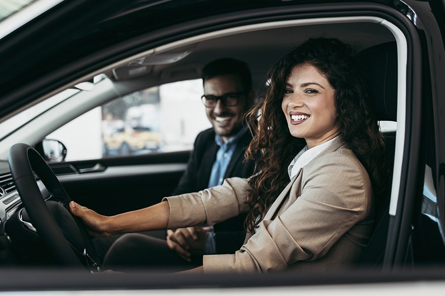 Personal Insurance - Happy Couple Choosing a New Car at a Showroom